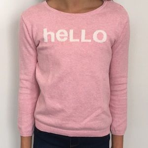 A pastel pink shirt that says “hello” on the front
